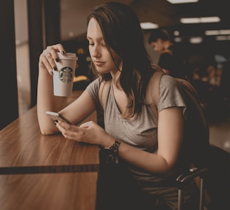 woman holding starbucks disposable cup and smartphone