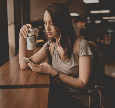 woman holding starbucks disposable cup and smartphone