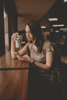 Woman enjoying coffee in a minimalist office setting with soft natural light.