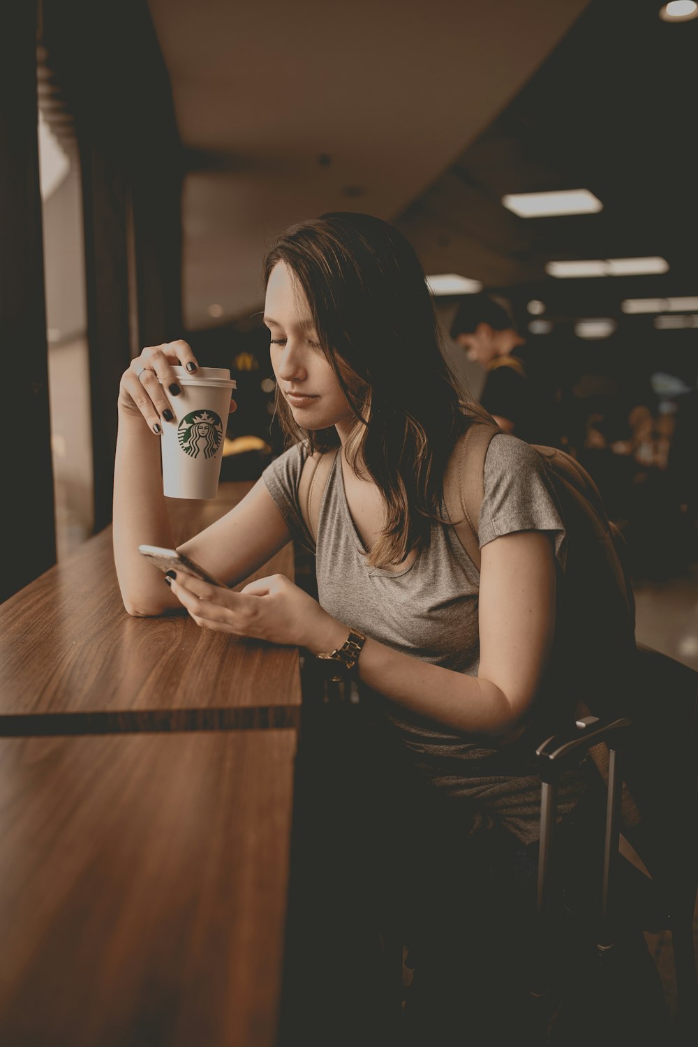 Donna che tiene la tazza usa e getta Starbucks e lo smartphone