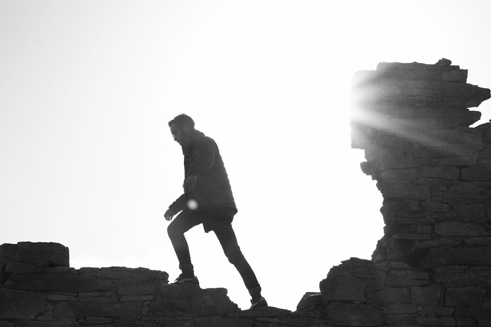 homem vestindo jaqueta andando na parede de tijolos