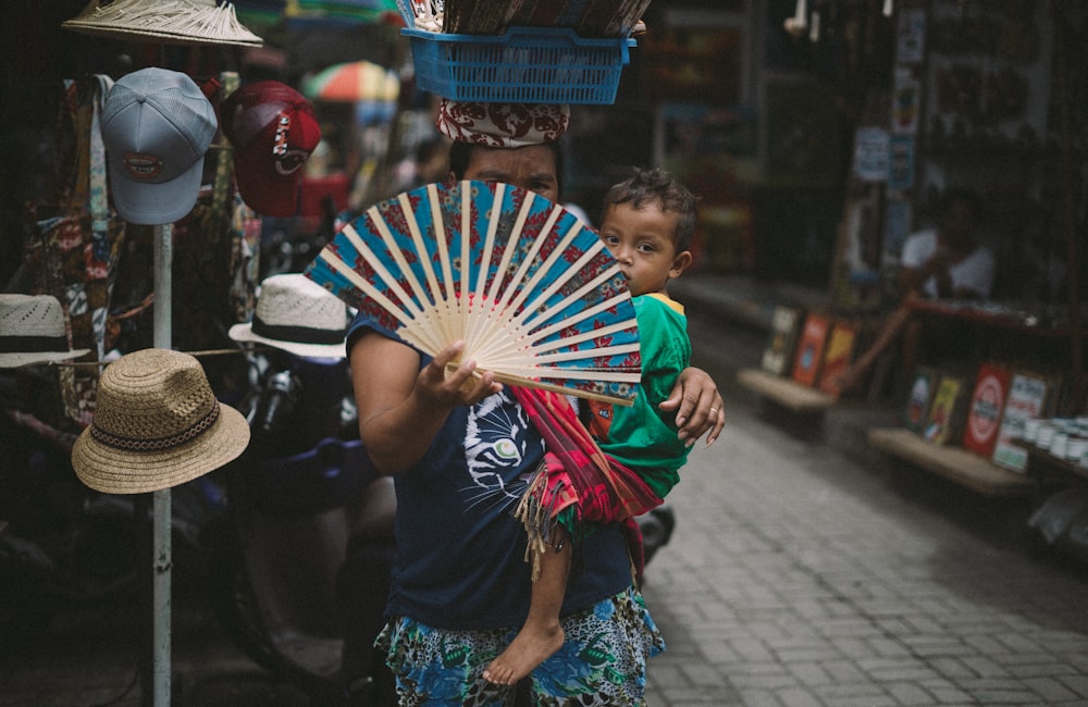 woman carrying baby hiding her face using hand fan