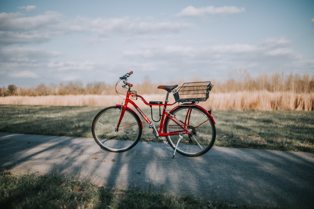 vélo de banlieue rouge sur la route entre les champs d’herbe pendant la journée