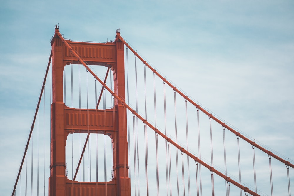 brown suspension bridge under blue and white sky