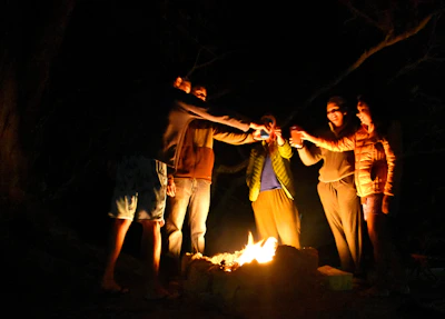 A joyful group enjoying brutto spirito drinks around a cozy fire.