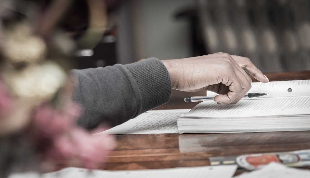 person putting pen on book