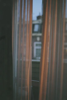 Elegant black blackout curtains framing a large window with a cityscape view at dusk.