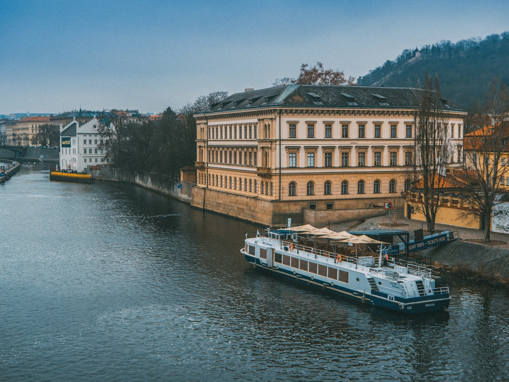 white and brown boat near river next to brown building during daytime