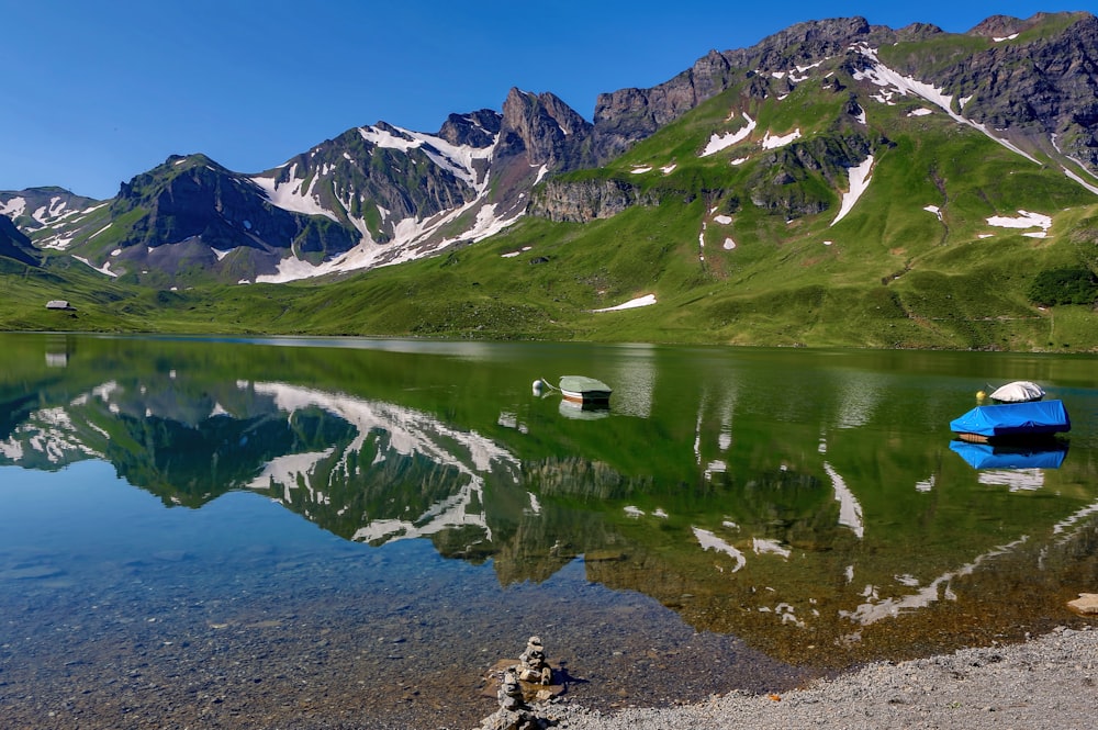 blue boat on bodies of water near mountain under blue sky at daytime