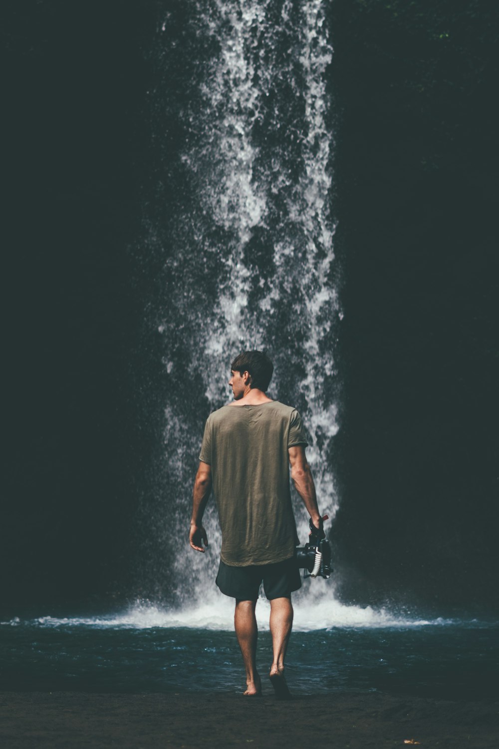 homme marchant près des chutes d’eau