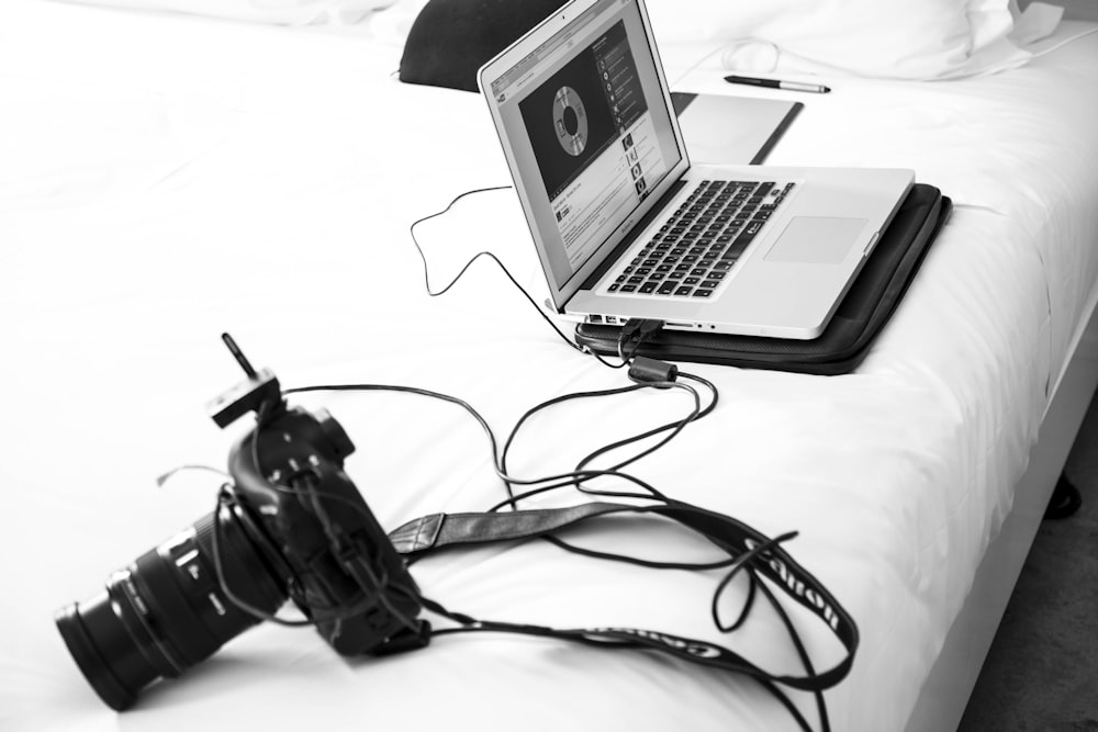 fotografia in scala di grigi di una fotocamera DSLR e di un MacBook Pro