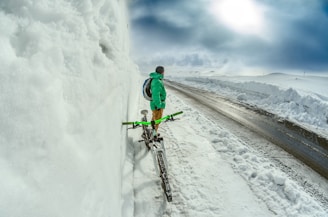 man standing besides green bicycle