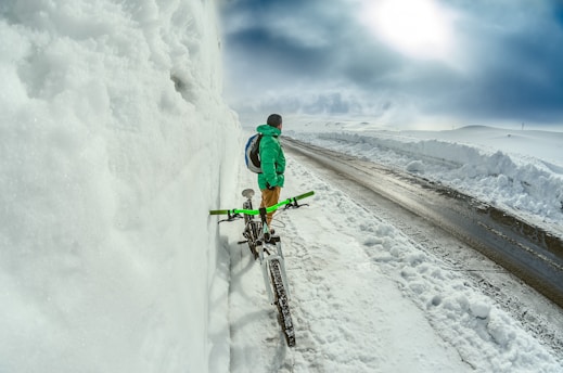 man standing besides green bicycle