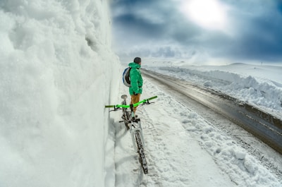 man standing besides green bicycle