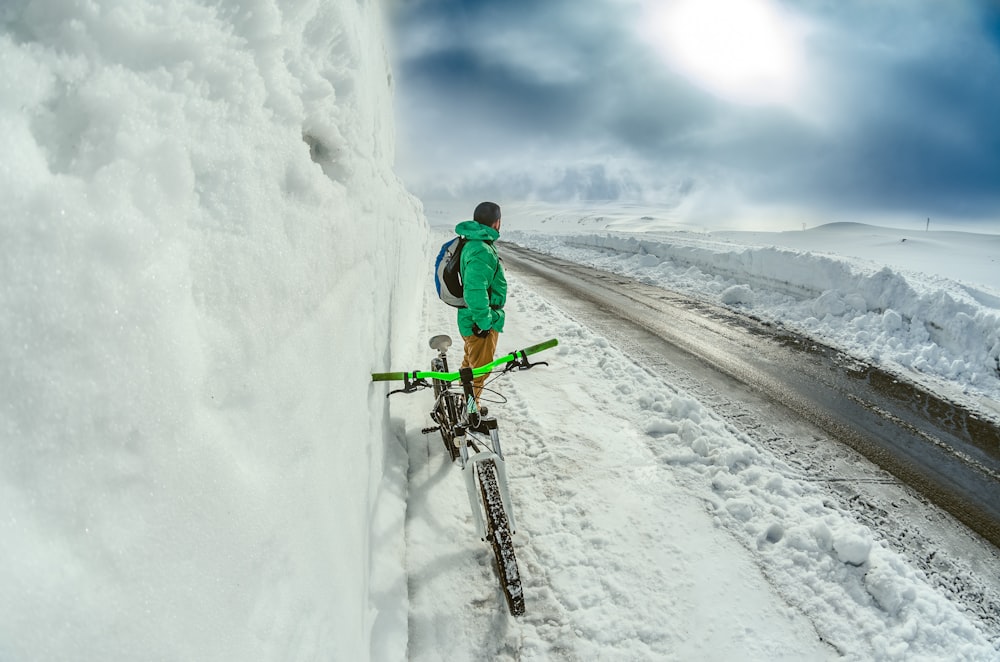 man standing besides green bicycle