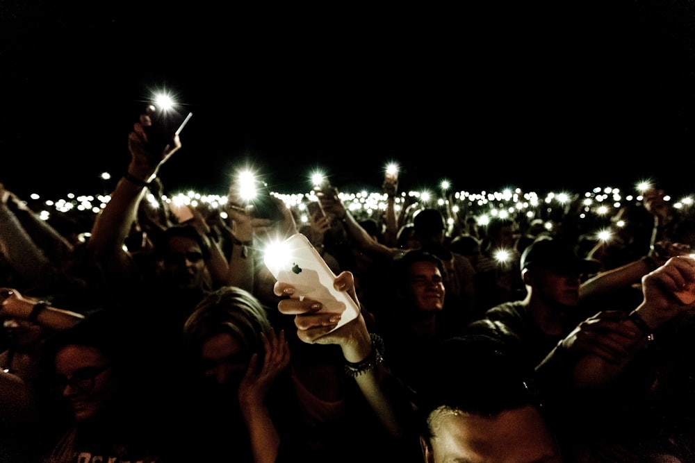 懐中電灯の中でスマートフォンを手にする群衆