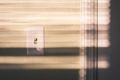 A hand adjusting a smart switch on a wall with ambient lighting in the background.