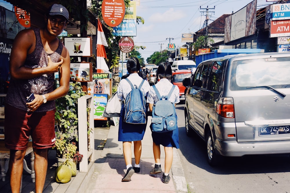 two girls walking on sidewalk during daytime