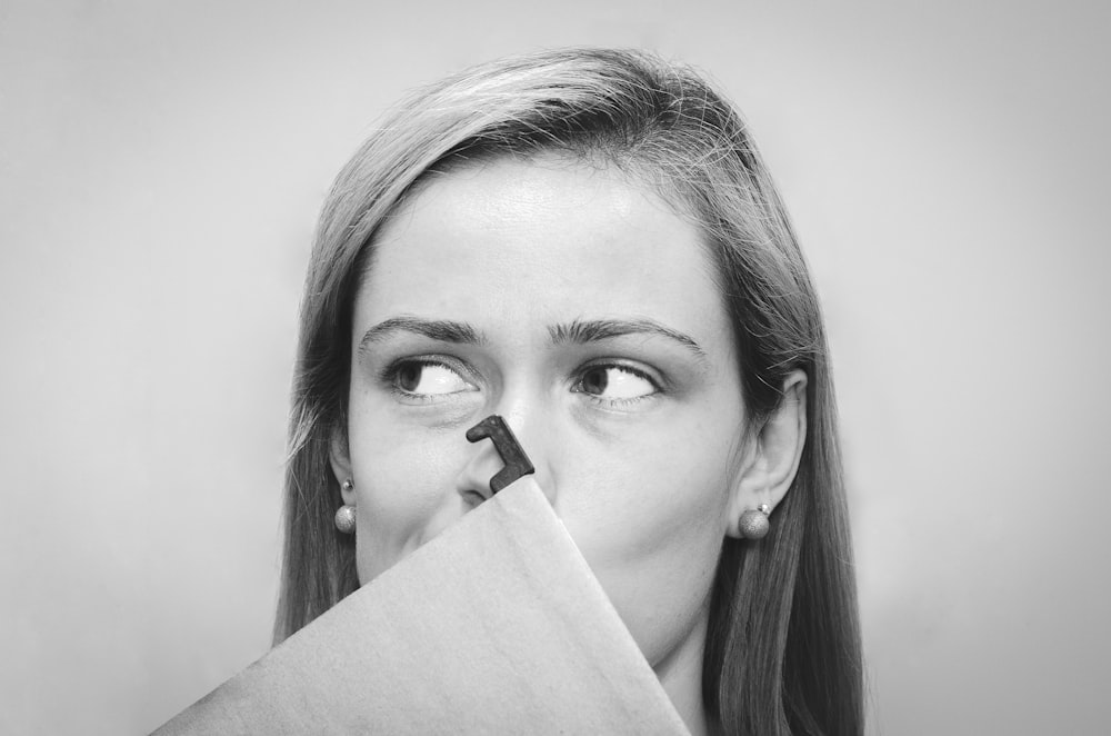 grayscale photography of woman with earrings covering her mouth