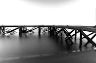 Black and white photo of an old wooden pier stretching into the sea.