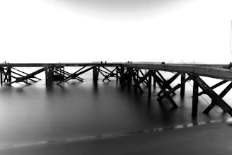 Black and white photo of an old wooden pier stretching into the sea.