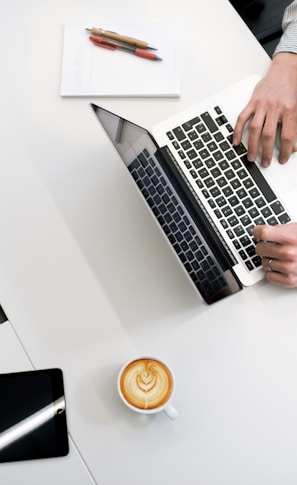 person using laptop on white wooden table