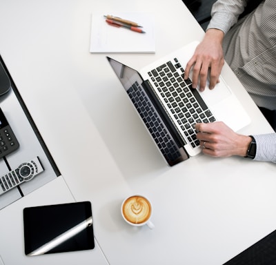 person using laptop on white wooden table