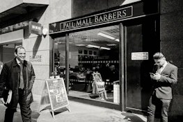 Smiling barber standing proudly inside Top Looks Barbers shop.