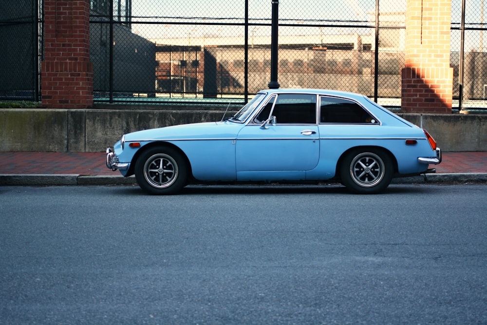 blue classic 3-door hatchback on gray concrete road