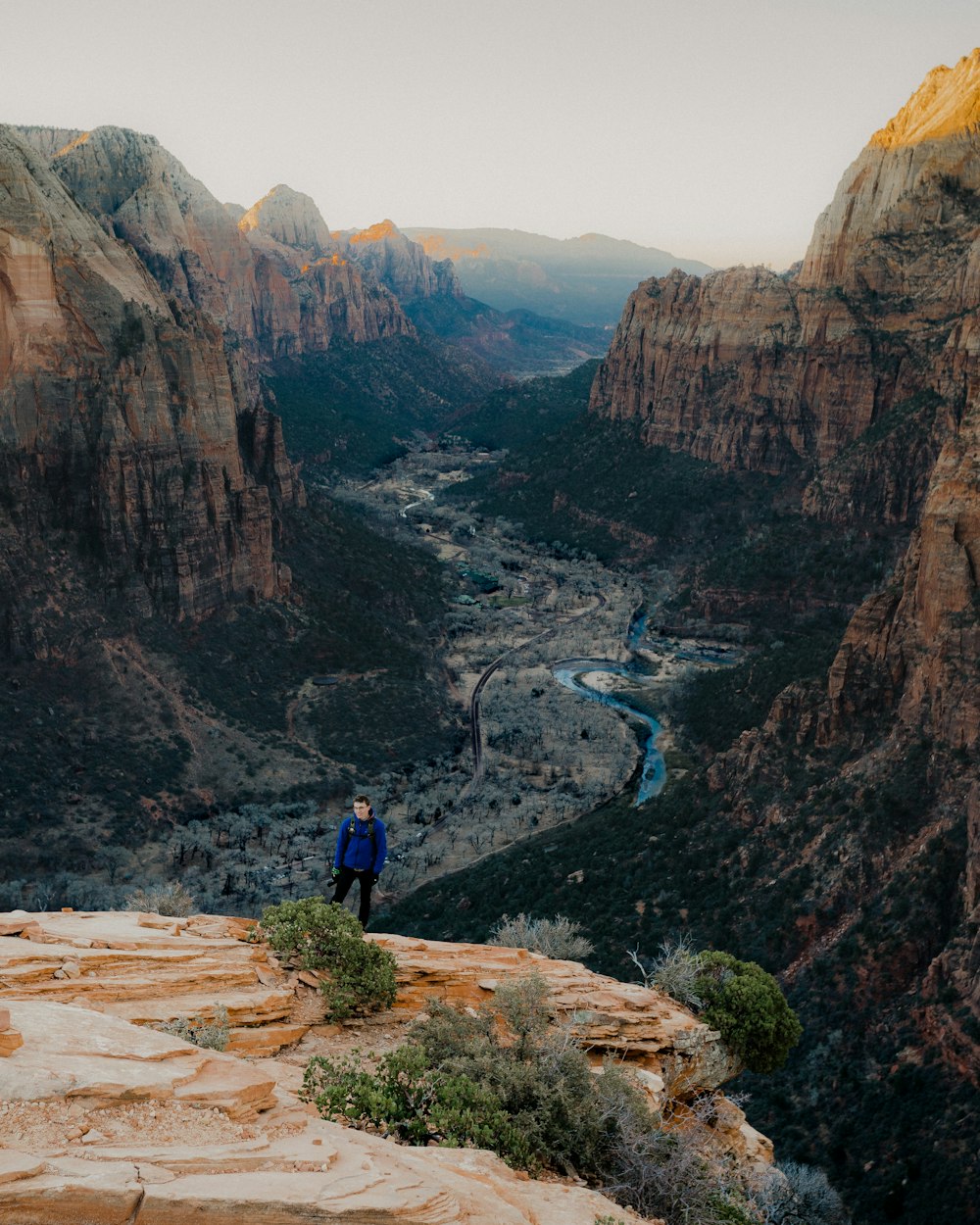 man standing on cliff under gray clouds