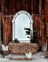 gray framed leaning mirror with hay and potted green leaf plant