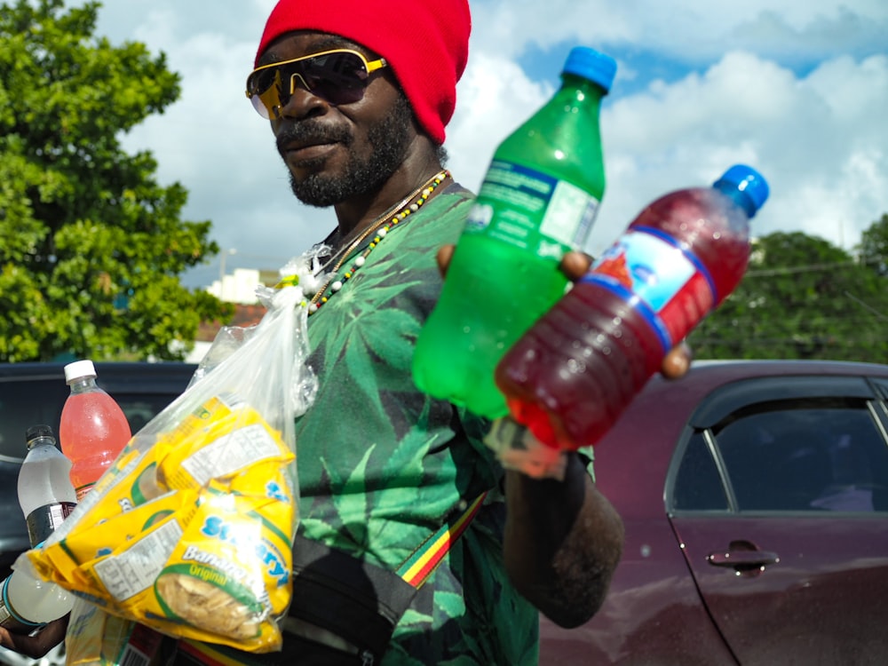 man wearing green t-shirt holding two Sprite and blue labeled bottles