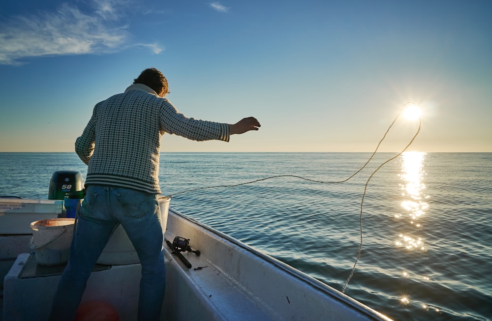 man standing on boat throwing rope on water