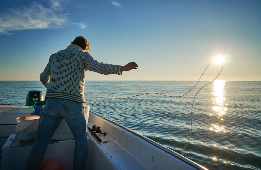 An angler casting off the back of a boat at sunrise
