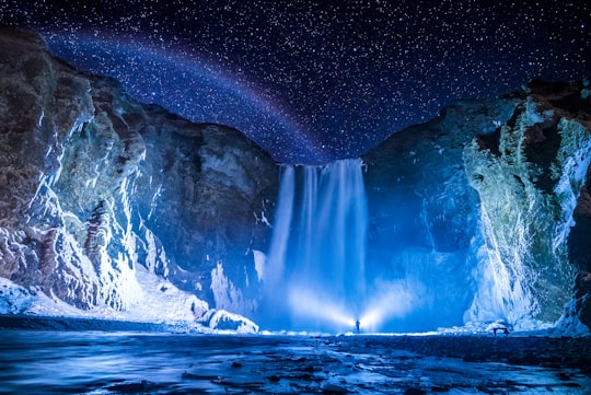 person in front of waterfalls during nighttime in Skógafoss Iceland