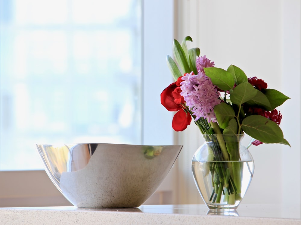 gray stainless steel bowl beside red and pink petaled flower centerpiece