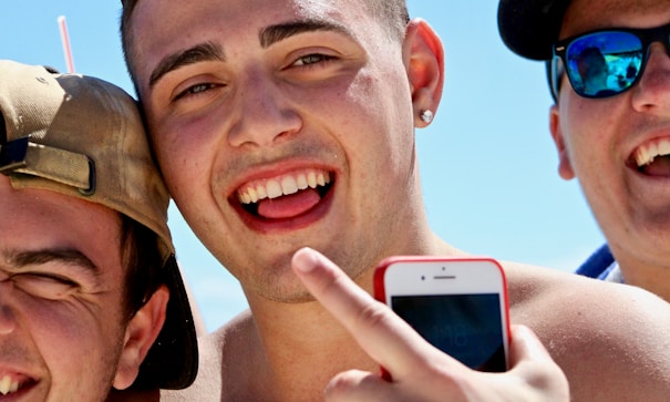 man holding iPhone in between two men