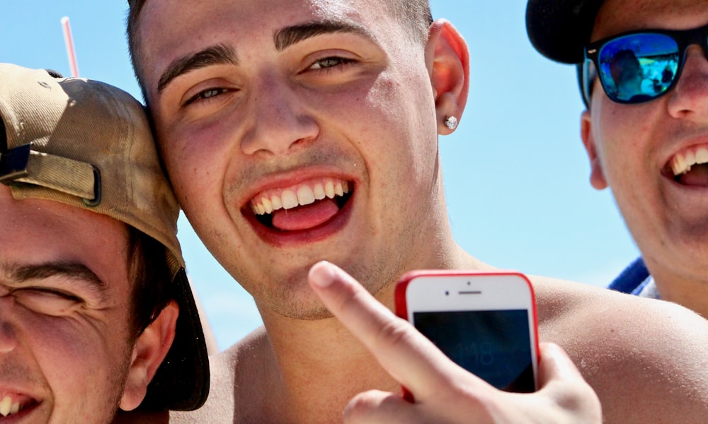 man holding iPhone in between two men