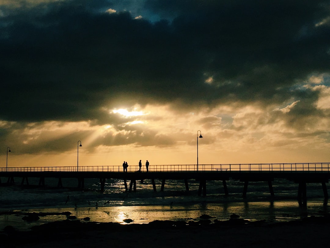 silhouette of four people standing on sea dock