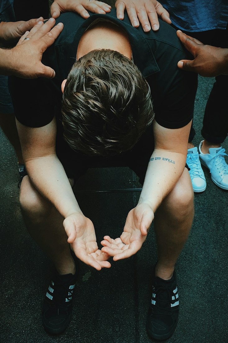 Men gathered around a seated man, praying over him