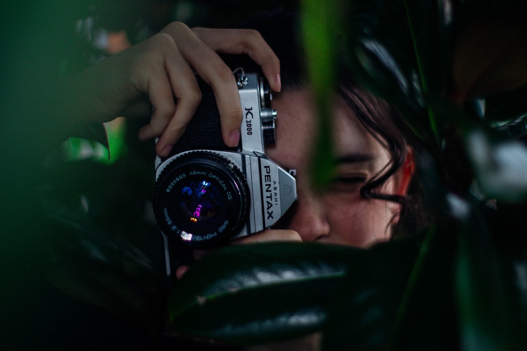 close up photography of woman hiding on trees while taking a picture