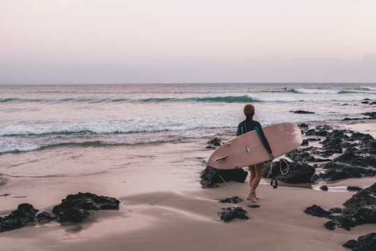 woman carrying surfboard on the seashore in Byron Bay Australia