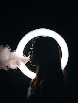 woman standing beside round lightbulb while smoking
