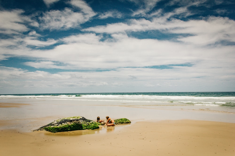 photo of two women on shore under cloudy sky