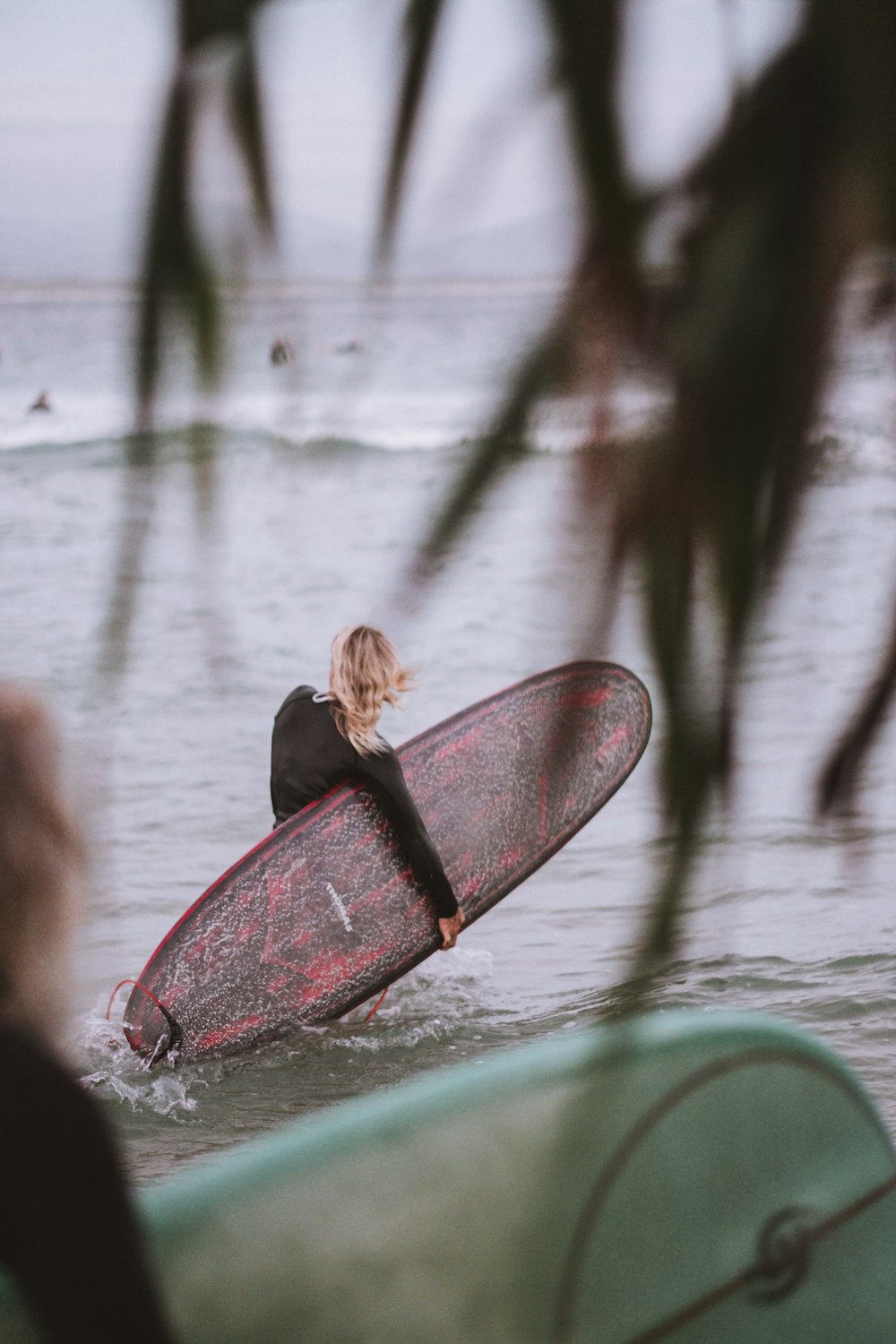 woman carrying pink surfboard on body of water
