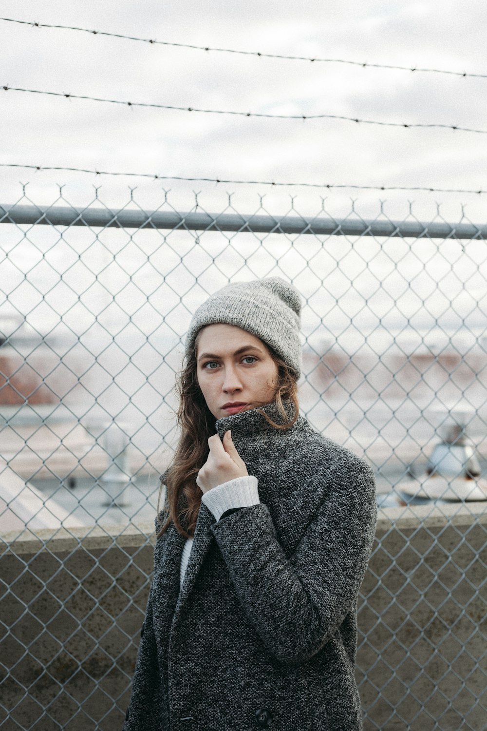 femme debout près de la clôture à mailles losangées en acier gris