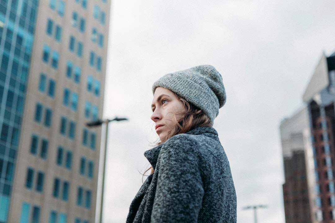 woman wearing gray coat knit cap standing near building during daytime