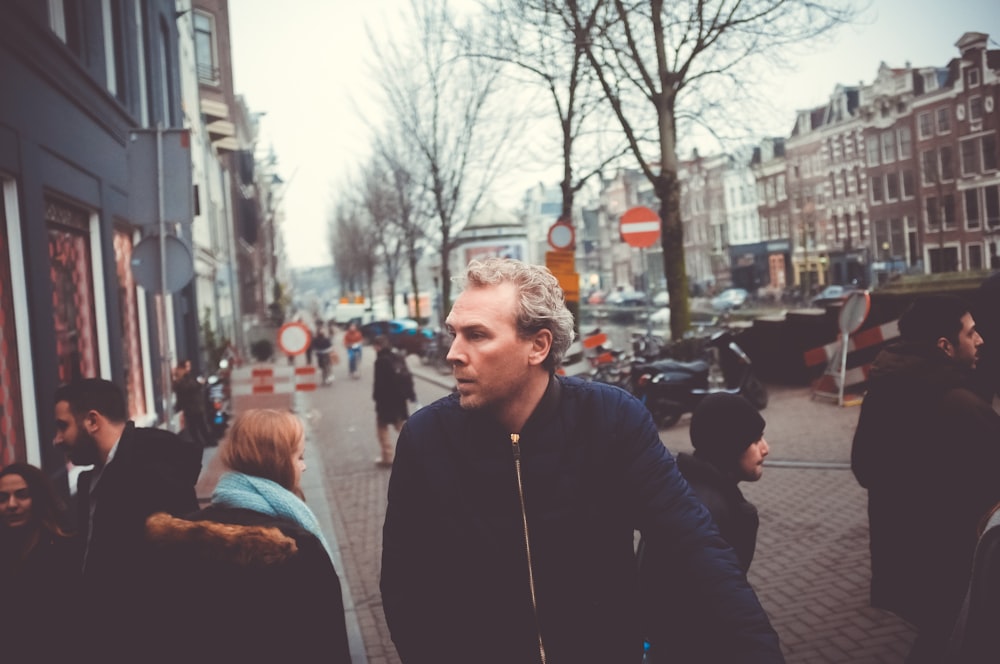 man walking in the middle of group of people in a pavement