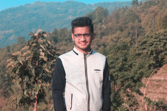 man in white full-zip jacket taking a photo on cliff in Dhankuta Nepal