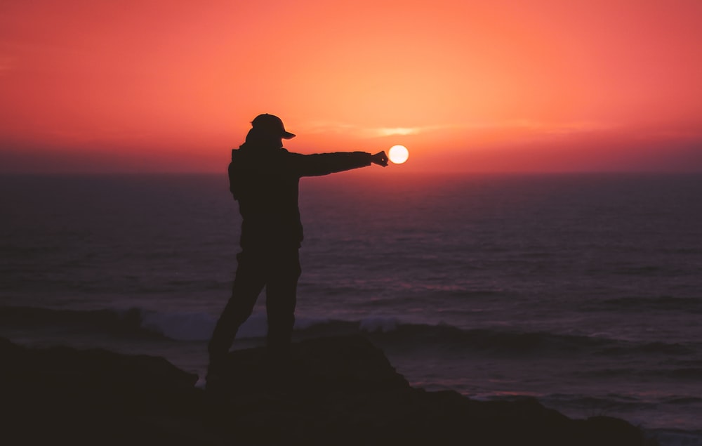 person standing on rock near body of water